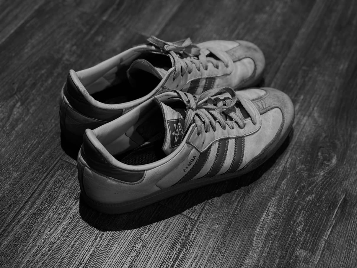 Used Adidas Samba shoes on a wooden surface.