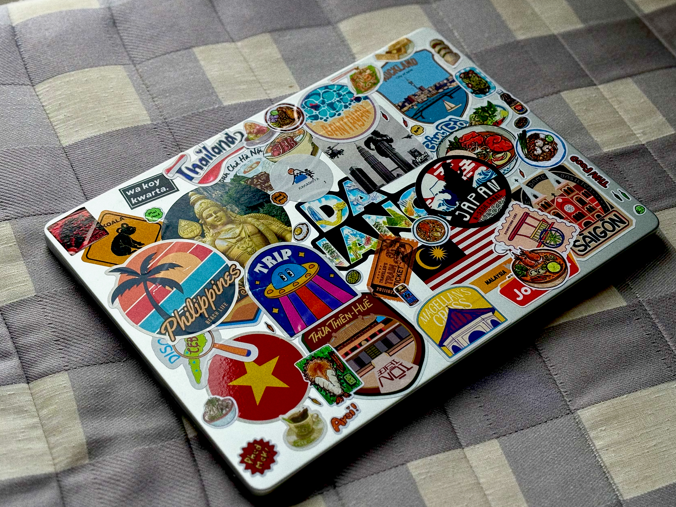 A Macbook with lots of travel stickers on the lid.